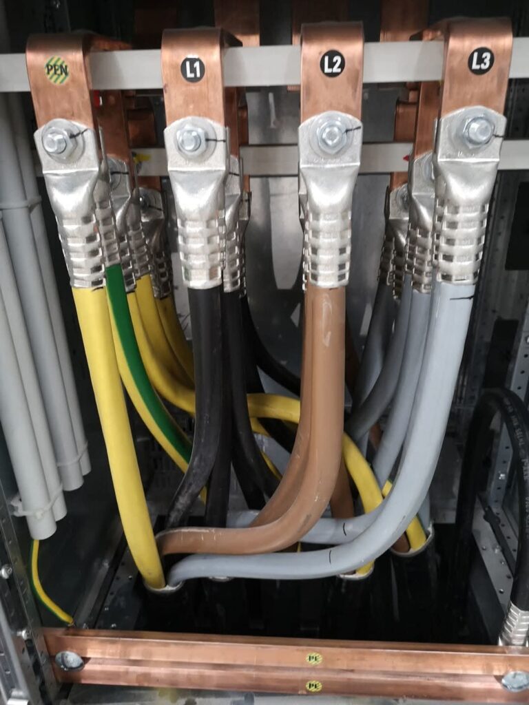 Leistungsanschlüsse mit Kupferschienen und gekennzeichneten Kabeln im Schaltschrank